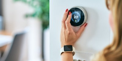 Žena nastavuje termostat na zdi