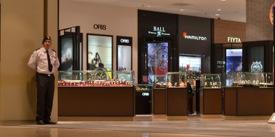 Ochranka stojící v nákupním středisku vedle obchodů s luxusním zbožím