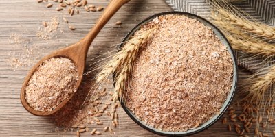 Pšeničné otruby v misce a v dřevěné lžíci, pšeničné klasy