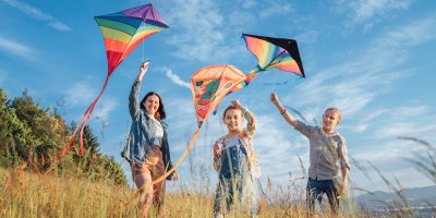 Trojice dětí s létajícími draky na poli