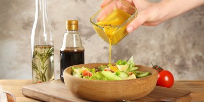 Žena lije hořčici na salát