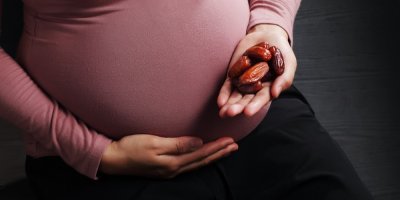 Těhotná žena drží datle v ruce
