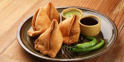 Talíř s taštičkami samosa, omáčkami a chilli papričkami