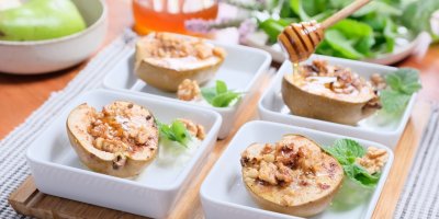 Pečené hrušky s medem a ořechy naservírované v miskách 