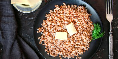 Uvařené kroupy s máslem na černém talíři