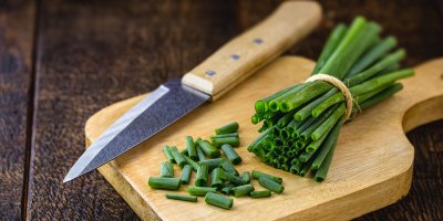 Prkénko s nakrájenou jarní cibulkou a nožem