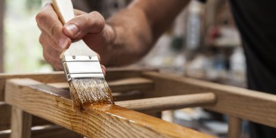 Člověk natírá nábytek olejem