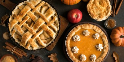 Tři různé dýňové koláče, kolem jsou dýně, jablka, skořice