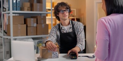 Žena si jde k výdejnímu pultu vyzvednout od muže balík