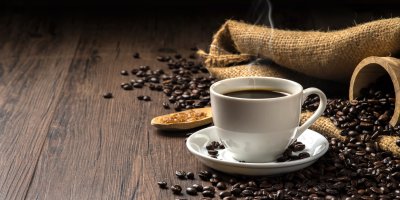 Šálek horké kávy mezi kávovými zrny
