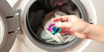 Ruka dává kapsli do pračky