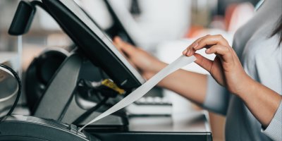 Žena si bere účtenku ze samoobslužné pokladny