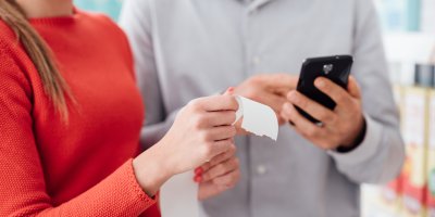 Dva lidé si prohlíží papírovou účtenku a mobilní telefon