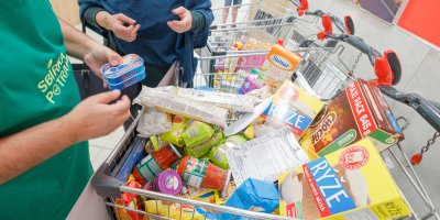 Dobrovolník Sbírky potravin a zákaznice u nákupních vozíků plných zboží