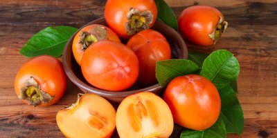 Ovoce kaki v misce a kolem ní