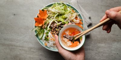 Pokrm, ruce drží v hůlce maso a rybí omáčku