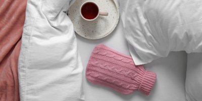 Nahřívací lahev a šálek s čajem v posteli