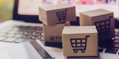 Malé balíčky se zbožím u otevřeného notebooku s e-shopem