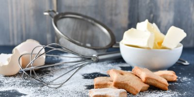 Perníčky a mouka, v pozadí metlička a miska másla