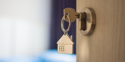 Klíč s přívěskem ve tvaru domečku v zámku vstupních dveří