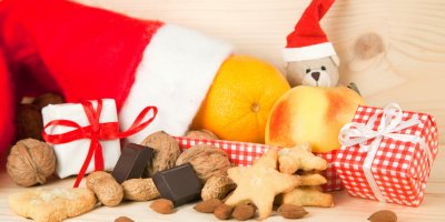 Vánoční čepice, plyšový medvídek, malé zabalené dárky, ořechy, čokoláda, pomeranč, jablko