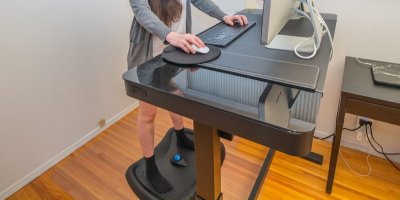 Žena stojí u počítače na protiúnavové podložce