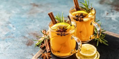 Dvě sklenice bílého punče s plátky citronu, hruškou a kořením