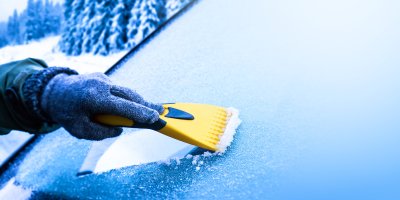 Ruka škrábající námrazu z čelního skla