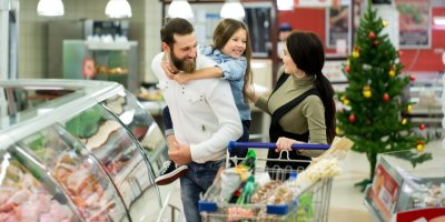Rodina nakupuje v supermarketu se stromečkem v pozadí
