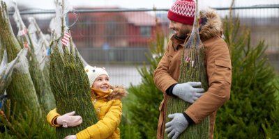 Tatínek s dcerou drží zabalené vánoční stromky