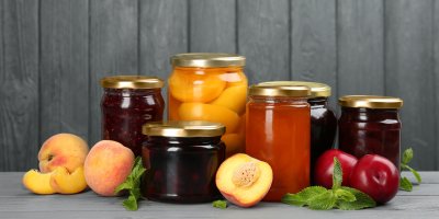 Sklenice s džemy a zavařeným ovocem a ovoce – broskve, meruňky a jablka