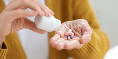 Žena si do dlaně sype vitamínové doplňky