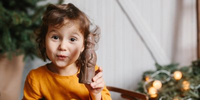 Dítě drží rozbalenou čokoládovou figurku Mikuláše