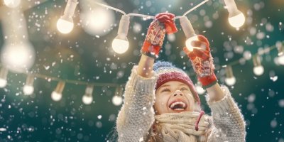 Šťastné dítě věší venku vánoční osvětlení