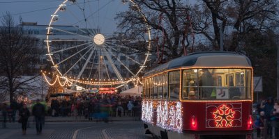 Vánoční tramvaj v popředí vánočních trhů a osvíceného ruského kola