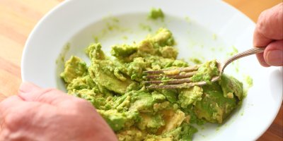 Člověk rozmačkává avokádo vidličkou