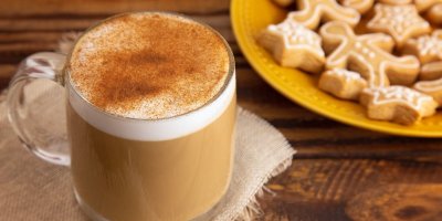 Latté s pěnou ozdobenou perníkem a vedle vánoční perníčky