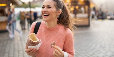Rozesmátá žena jí trdelník na trhu