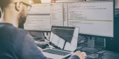 Muž sedí před několika monitory