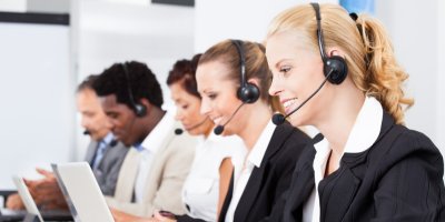 Několik lidí před notebooky se sluchátky na uších