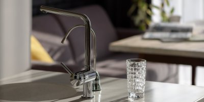 Dvojice kohoutků u dřezu a sklenice s vodou