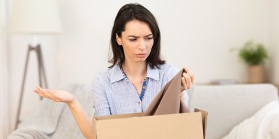 Žena se znepokojeně kouká na hnědou halenku v krabici