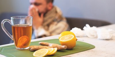 Zázvorový čaj s citronem a v pozadí nemocný muž