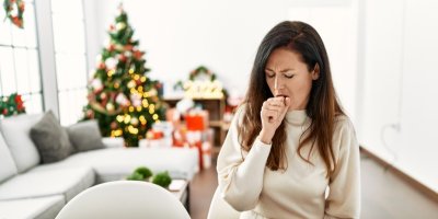Žena kašle a v pozadí je vánoční stromeček