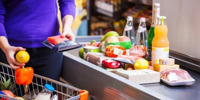 Žena vykládá nákup na pás u pokladny supermarketu