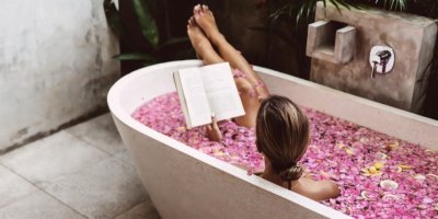 Žena se koupe ve vaně plné okvětních lístků