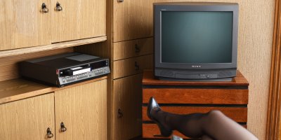 Žena v silonkách sedící v křesle před retro televizí Sony