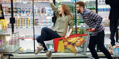 Žena a muž závodící v supermarketu s nákupním vozíkem