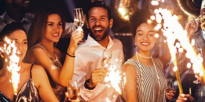 Skupina slavících přátel držících sklenice sektu a prskavky