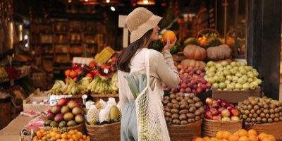 Žena čuchá k pomeranči na trhu